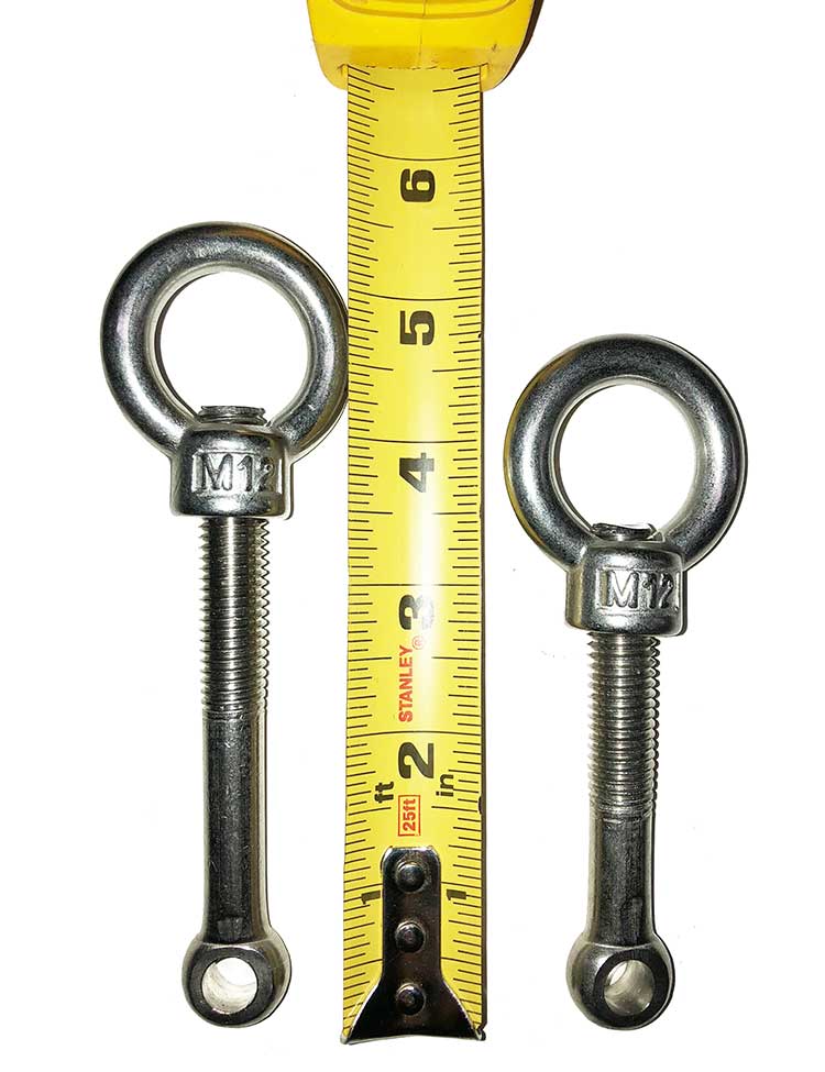 Two stainless steel eye bolt screws next to a yellow measuring tape.
