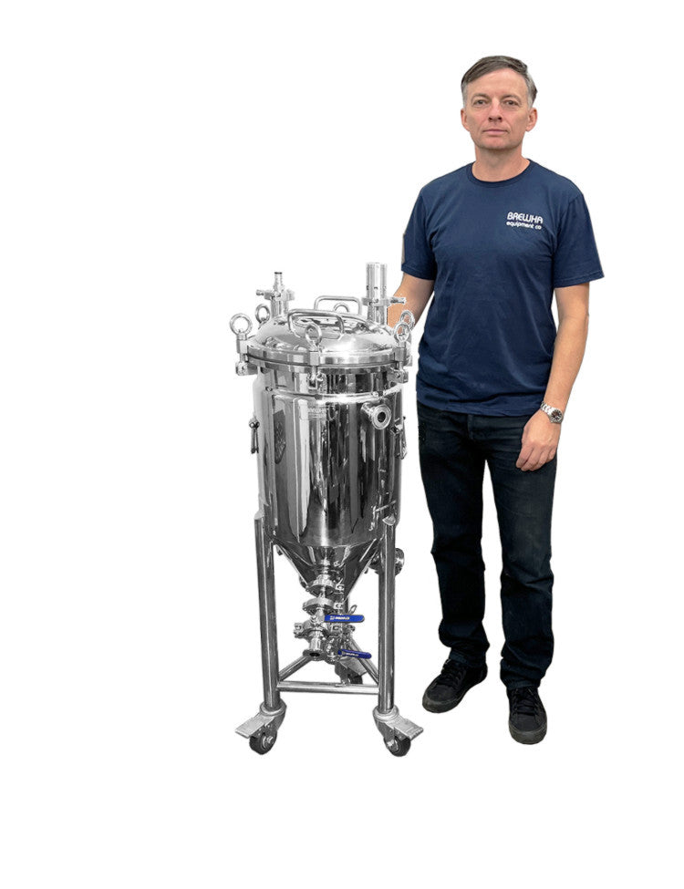 A person standing next to a stainless steel, jacketed, unitank conical fermenter with completely removable lids, heater ports, and polyurethane insulation.